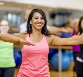 A woman smiles as she works out in a group exercise class.