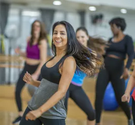 A group of people smiling in an indoor Zumba class.