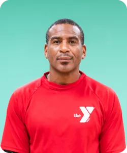 A photo of Fred Thorpe, personal trainer at the Stoney Creek YMCA. He is wearing a red shirt with a white YMCA logo on the upper left of his chest and looking into the camera.