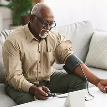 Senior African Male Measuring Arterial Blood Pressure Having Hypertension Indoor