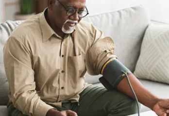 Senior African Male Measuring Arterial Blood Pressure Having Hypertension Indoor