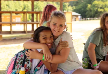 two girls embracing each other excitedly at camp 