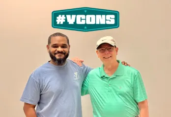 Two gentleman smiling for a photo with the graphic YCON above them