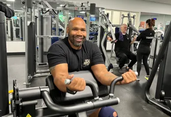 Gentleman smiling at the camera while on weight equipment