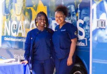 Two nurses posing for a picture outside a Wellness bus