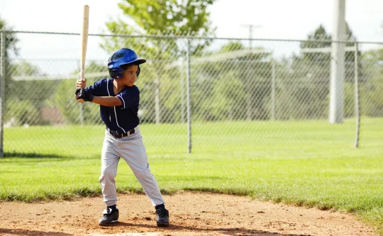 A young boy prepares to hit the ball while playing baseball.