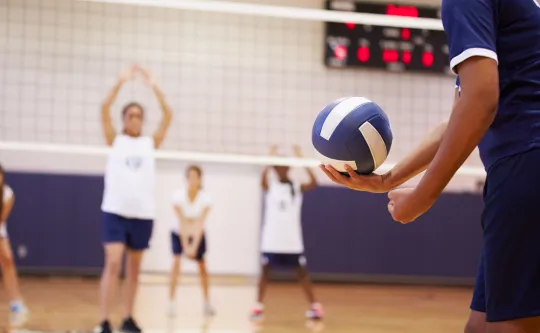 A volleyball player preparing to serve a volleyball during a match.