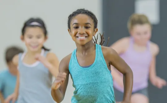 A group of children running in a gym.