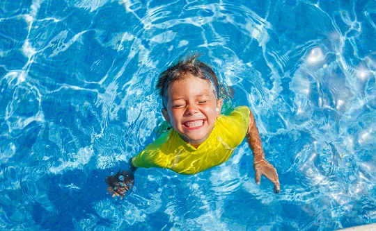 Boy in pool smiling. 