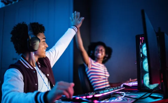 Two teens high-fiving while playing eSports together.