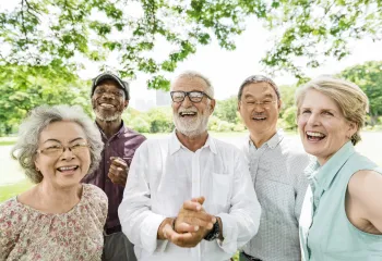 A diverse group of seniors standing outdoors together. They are smiling.