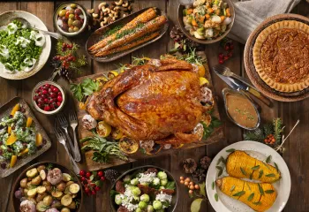 A holiday meal with a spread of foods like turkey, cranberries, and pies.