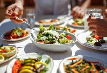 People eating a meal at a restaurant. There is a salad at the center of the table featured in the photo.