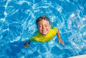 Boy in pool smiling.