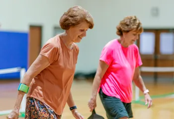 Two women playing pickleball together on a team.
