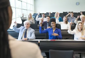 A teacher leading a sign language class with a group of adults.