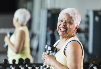 A senior woman holding hand weights while working out.
