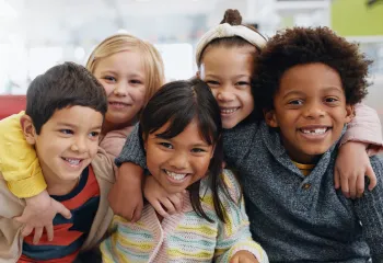 A diverse group of young children sitting together and smiling at the camera.