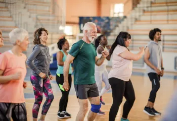 A diverse group of people dancing together in a gym.
