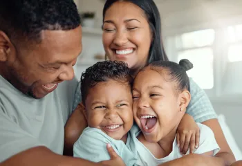 Parents and their two small children laughing together.