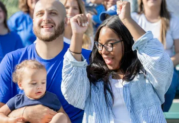 A mother and father at a sporting event with their young child.