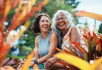 Two women sitting outdoors laughing together.