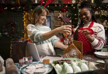 Two women making a gingerbread house