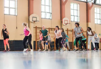 A diverse group of people dancing together in a gym.