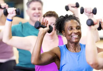 A senior woman in a group exercise class. The class is using handweights.