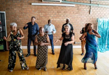 A group of senior friends laughing and dancing together.