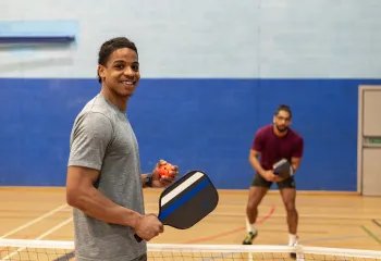 Two men in gym playing pickleball