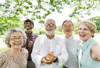 A group of seniors standing outdoors laughing together.