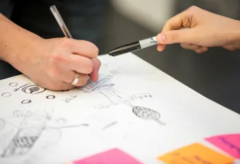 Two people drawing a life map on paper. The photo is a close up of two hands.