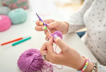 A close-up view of a woman's hands as she is crocheting.