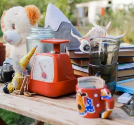 A photo of a collection of items on a wooden table. Some of the items include a mug, a stuffed bear, and a stack of books.