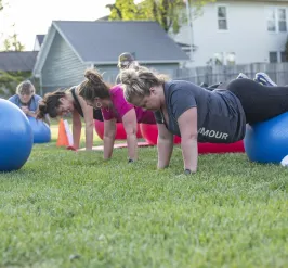 A group of women in an outdoor group exercise class at the Reidsville YMCA. They are balancing on exercise balls.