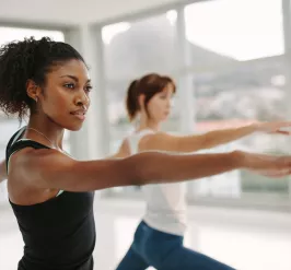 Two women in a yoga class holding a yoga pose and concentrating.