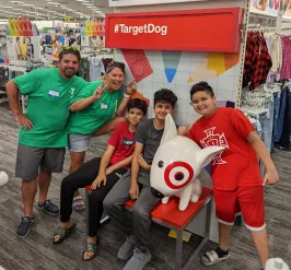 Two Bright Beginnings volunteers smile for a photo in Target with three children shopping for school supplies.