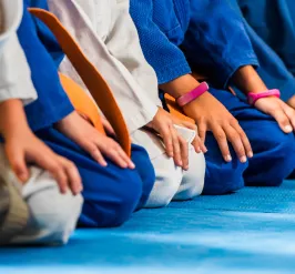 A photo of a group of children in a martial arts class. The photo is cropped to not show their faces.