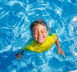 Boy in pool smiling. 