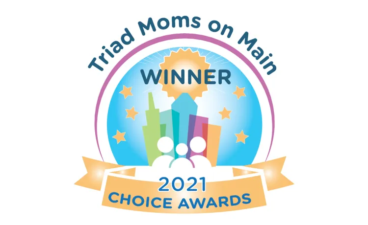 A logo for the Triad Moms on Main Choice Awards. It is a colorful illustration of buildings with white line illustrations of people in front of it. The text around the circle reads "Triad Moms on Main," above the buildings is the word "Winner," then the bottom yellow banner says "2021 Choice Awards" in blue text.