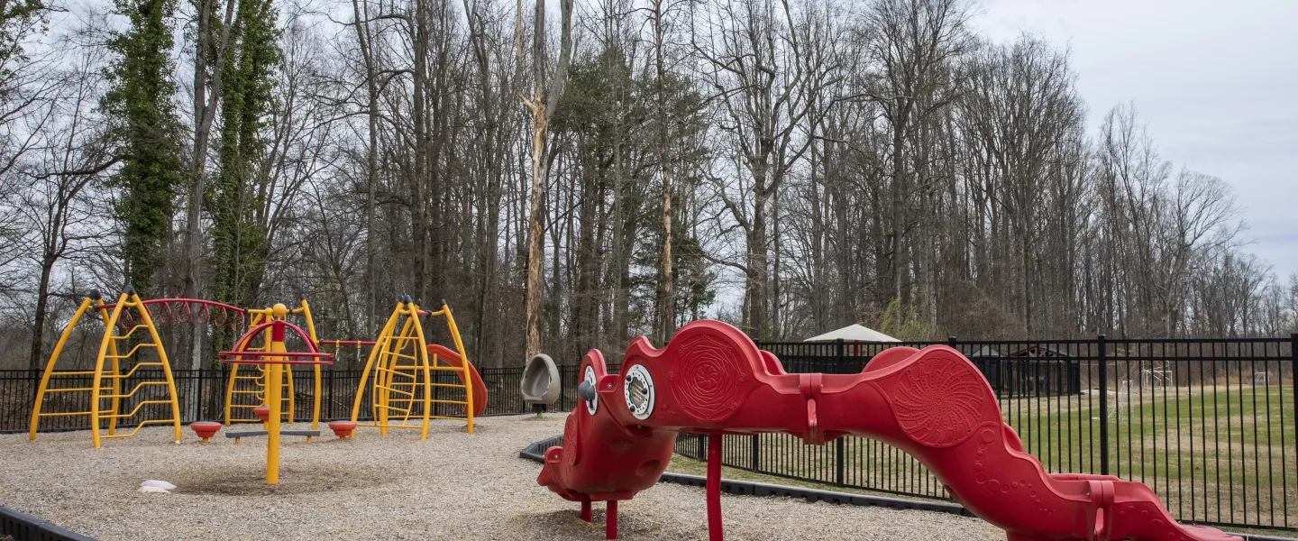 A photo of the playground at the Hayes-Taylor YMCA. There is a red slide with a yellow climbing gym.