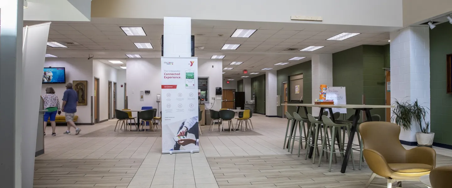 The lobby area at the Bryan YMCA. There are multiple tables with chairs.