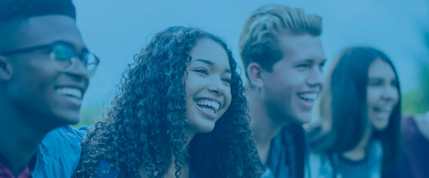 A group of four diverse teens smiling and laughing together.