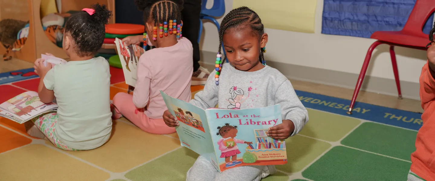 A young girl reading in the Hayes-Taylor YMCA's Kiddie College classroom.