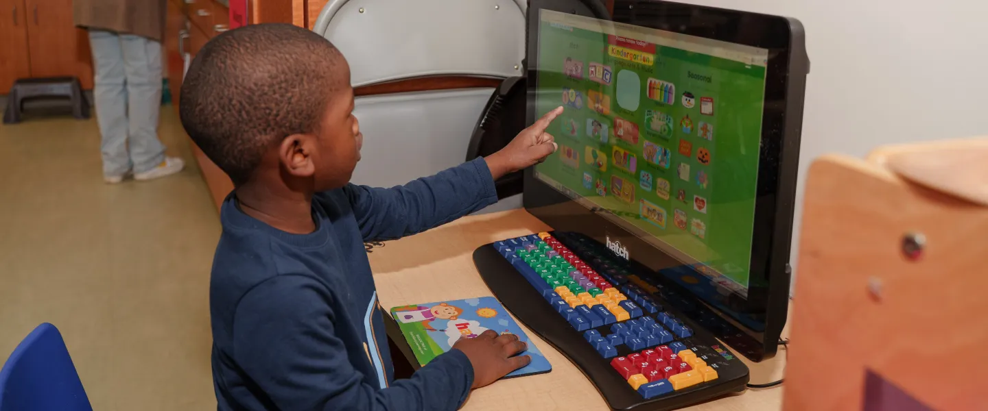 A young boy in the Hayes-Taylor YMCA's Kiddie College preschool program interacts with an educational game on a screen.