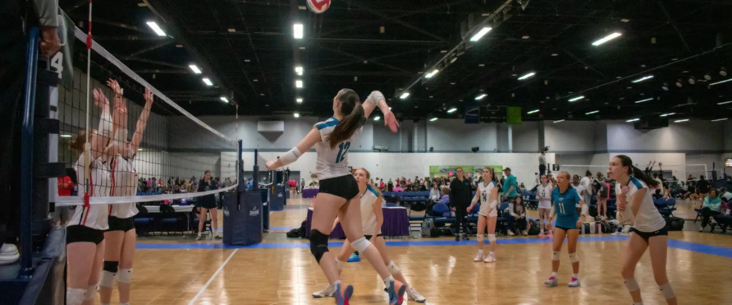 Carolina Spike Force volleyball athletes playing on court. One player jumping into air to hit ball