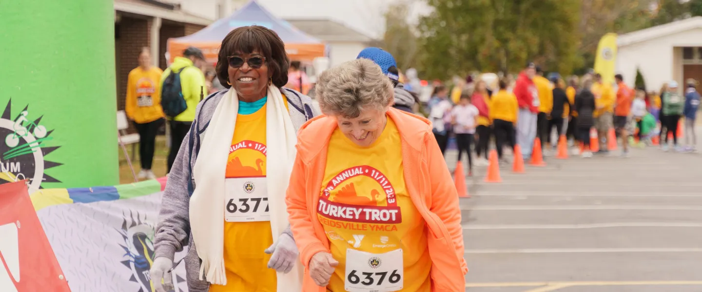 Two senior women walking together and laughing during the Reidsville Family YMCA Turkey Trot.