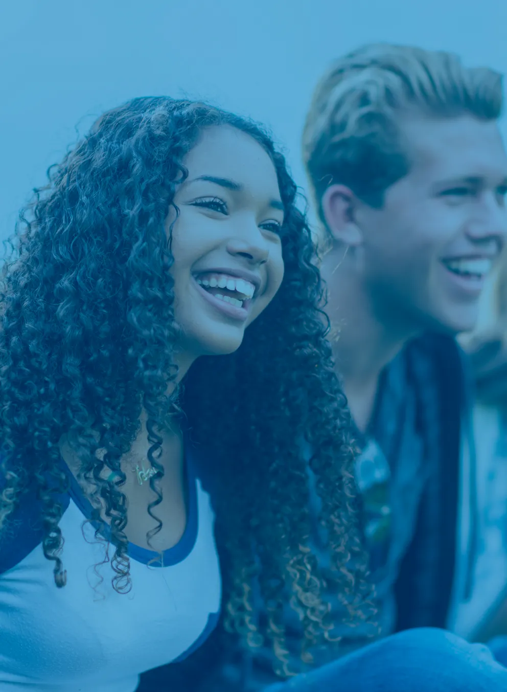 A group of four diverse teens smiling and laughing together.