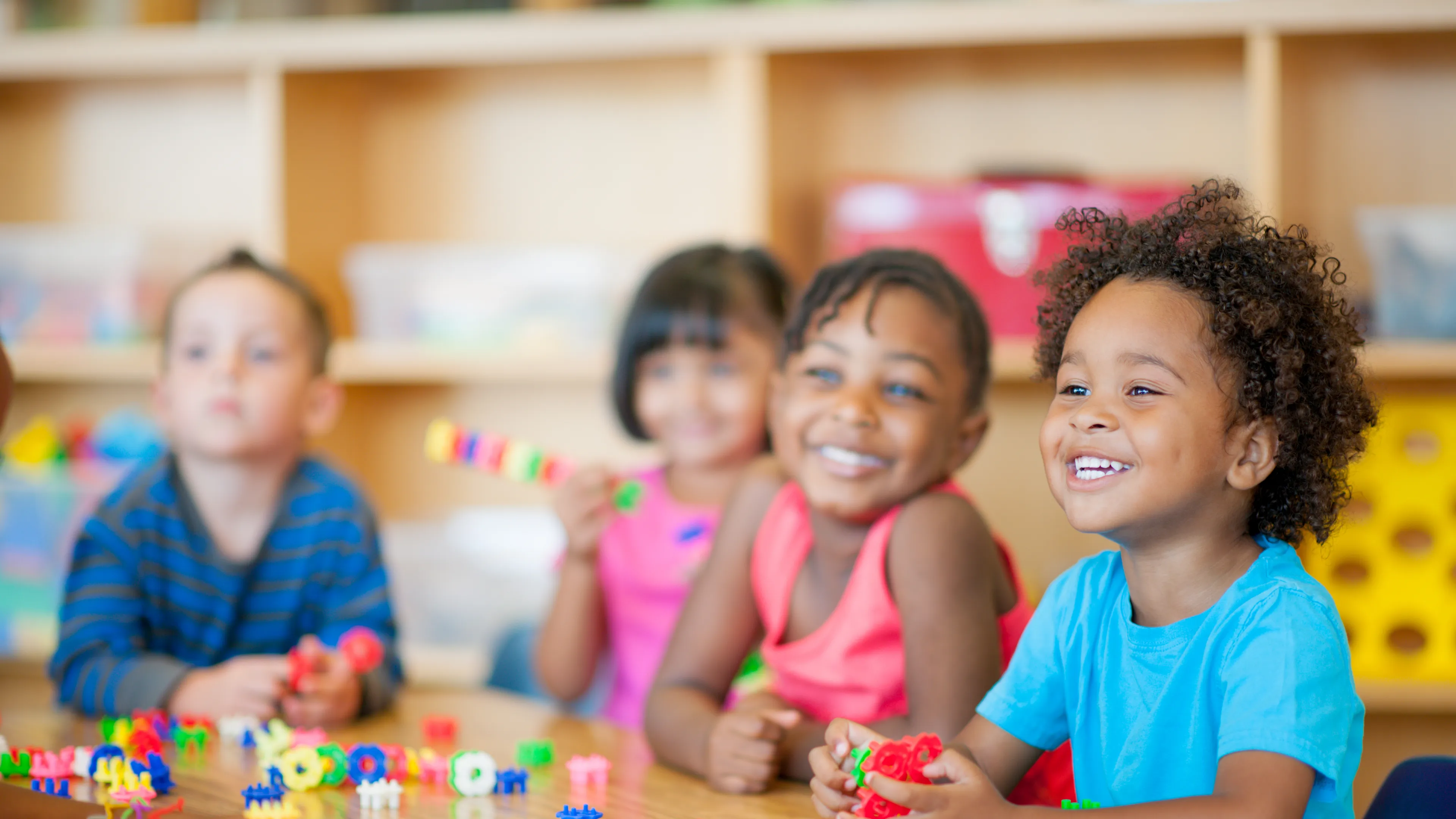 A diverse group of young children playing together at a table.